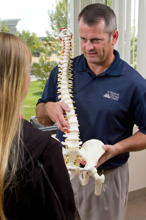 Education corner image, Physical therapist explaining to patient holding a skeleton or spine